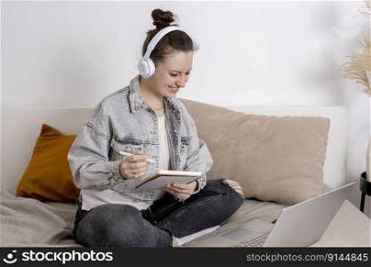 Young beautiful woman with casual clothes sitting on the bed at home with laptop computer and studying. Girl using e-learning platform to make a video call with her teacher. Distance education. Young beautiful woman with casual clothes sitting on the bed at home with laptop computer and studying. Girl using e-learning platform to make a video call with her teacher. Distance education.
