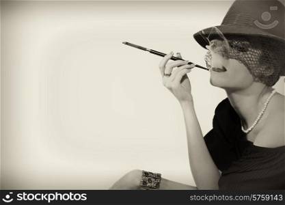Young beautiful woman with cigarette in mouthpiece in hat with veil