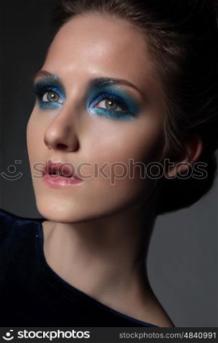 Young beautiful woman with fancy retro make-up. Bright blue eye shadow. Face close-up.