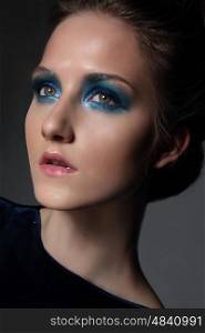 Young beautiful woman with fancy retro make-up. Bright blue eye shadow. Face close-up.