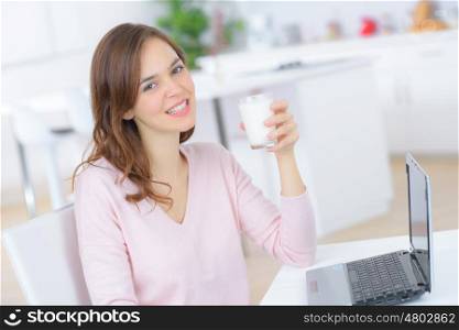 young beautiful woman with laptop while drinking a tea