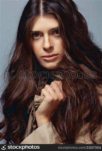 Young beautiful woman with long curly hair on blue background