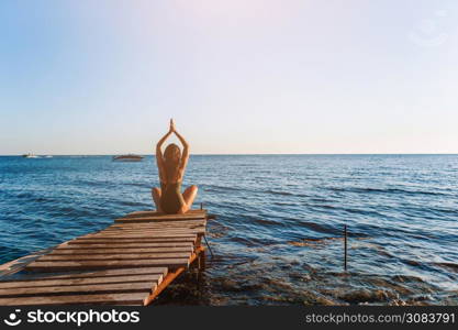 Young beautiful woman woman practicing yoga on the coast on the sunset. Young beautiful woman on yoga on the beach