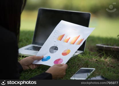 Young beautiful woman working outdoor in a public park. Working on laptop outdoors. Cropped image of female working on laptop while sitting in a park.