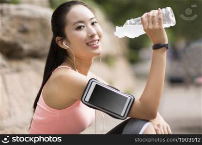 Young beauty drinking water and taking a rest after working out