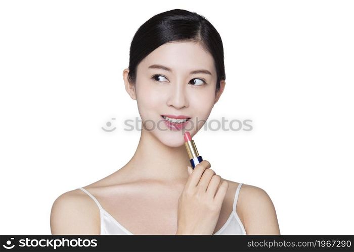 Young beauty putting on makeup and lipstick