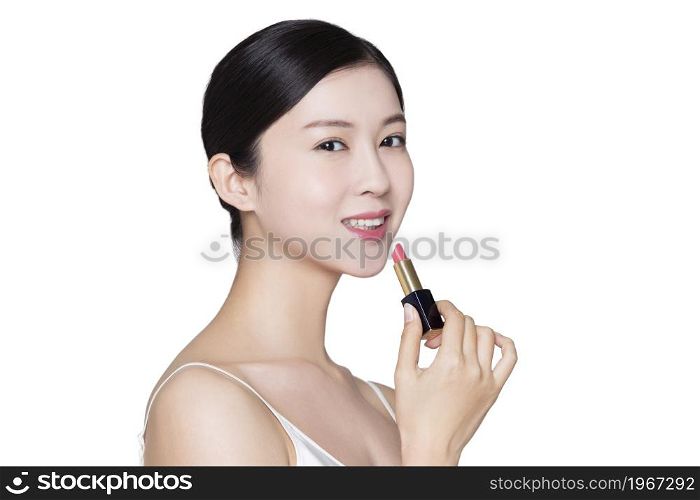 Young beauty putting on makeup and lipstick