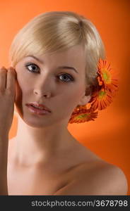 young beauty sweet blond girl with wuth gerbera in hair looking in camera