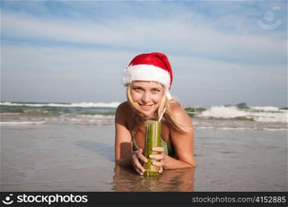 Young beauty woman in christmas hat laying on the beachfront