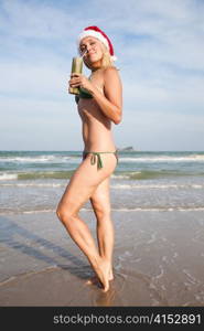 Young beauty woman with cocktail in christmas hat on the beach