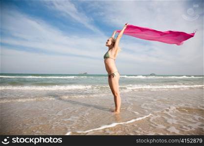 Young beauty woman with pink shawl on the beach