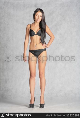 young bikini woman posing against gray background