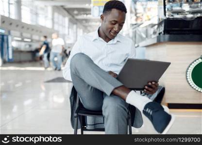 Young black businessman using laptop in car showroom. Successful business person on motor show, black man in formal wear. Black businessman using laptop in car showroom