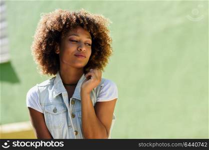 Young black woman, afro hairstyle, in the street. Girl, model of fashion, wearing casual clothes in urban background.
