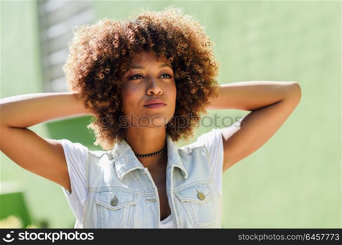Young black woman, afro hairstyle, in the street. Girl, model of fashion, wearing casual clothes in urban background.