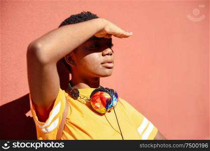 Young black woman covering with her hand the sun that falls on her eyes. Girl with very short hair.. Young black woman covering with her hand the sun that falls on her eyes.