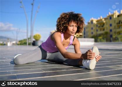 Young black woman doing stretching after running outdoors. Young black woman doing stretching after running outdoors. Girl exercising with city scape at the background. Afro hair.