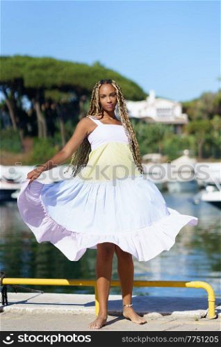 Young black woman walking along a seaport wearing a nice summer dress.. Black woman walking along a seaport wearing a nice summer dress.
