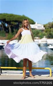 Young black woman walking along a seaport wearing a nice summer dress.. Black woman walking along a seaport wearing a nice summer dress.