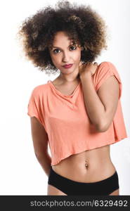 Young black woman with afro hairstyle. Girl wearing t-shirt and black panties. Studio shot.