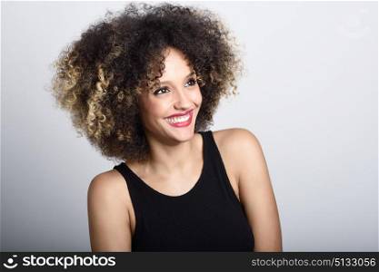 Young black woman with afro hairstyle laughing. Girl wearing black clothes. Studio shot.