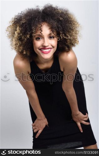 Young black woman with afro hairstyle laughing. Girl wearing black clothes. Studio shot.