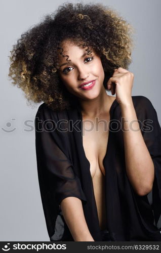 Young black woman with afro hairstyle laughing. Girl wearing black clothes. Studio shot.