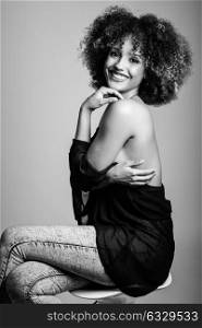 Young black woman with afro hairstyle laughing. Girl wearing black clothes. Studio shot. Black and white photograph