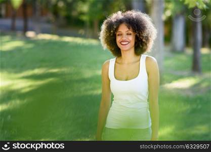 Young black woman with afro hairstyle laughing with eyes closed in urban park. Mixed girl wearing casual clothes.