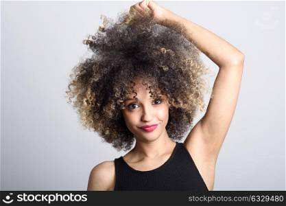 Young black woman with afro hairstyle smiling. Girl wearing black dress. Studio shot.