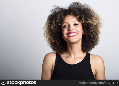 Young black woman with afro hairstyle smiling. Girl wearing black dress. Studio shot.