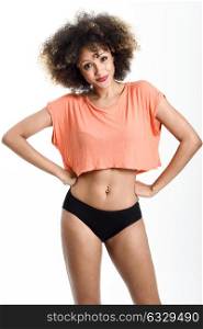 Young black woman with afro hairstyle smiling. Girl wearing t-shirt and black panties. Studio shot.