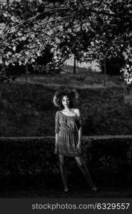 Young black woman with afro hairstyle standing in urban background. Mixed girl wearing casual clothes.