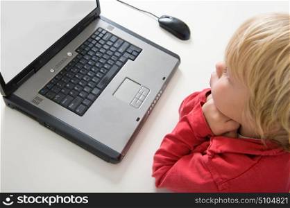 Young blond boy behind a well used laptop with selective focus