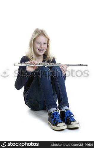 young blond girl sits holding flute in studio against white background