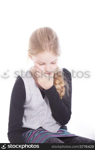 young blond girl thinking on floor of studio against white background