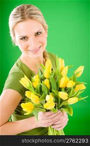 Young blond happy woman hold yellow tulips flower on green