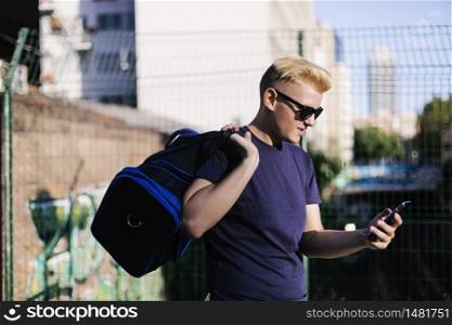 Young blond male using a cell phone on the street