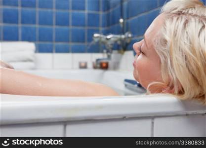 Young blond relaxed women in bathtub with eyes closed