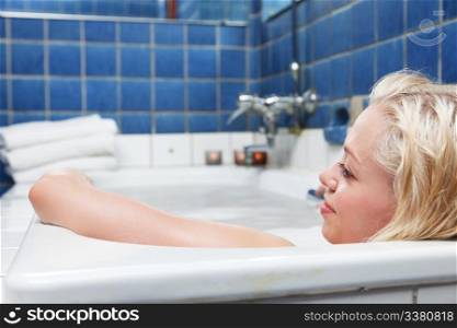 Young blond smiling women in bathtub and relaxing