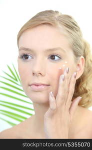 Young blond woman applying anti-wrinkles cream