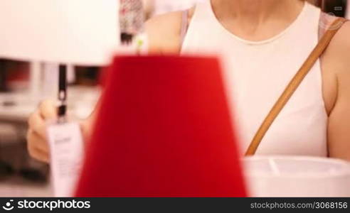 Young blond woman choosing lamps by the lamp store