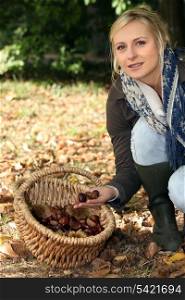 Young blond woman gathering chestnuts