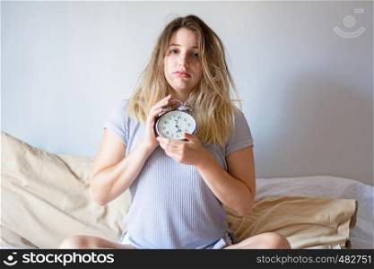 Young blond woman hates waking up early in the morning.