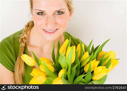 Young blond woman hold bunch of yellow tulips flower