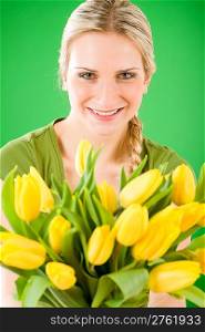 Young blond woman hold yellow tulips flower on green