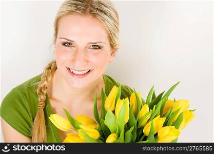 Young blond woman hold yellow tulips flower on white