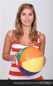 Young blond woman holding beach ball