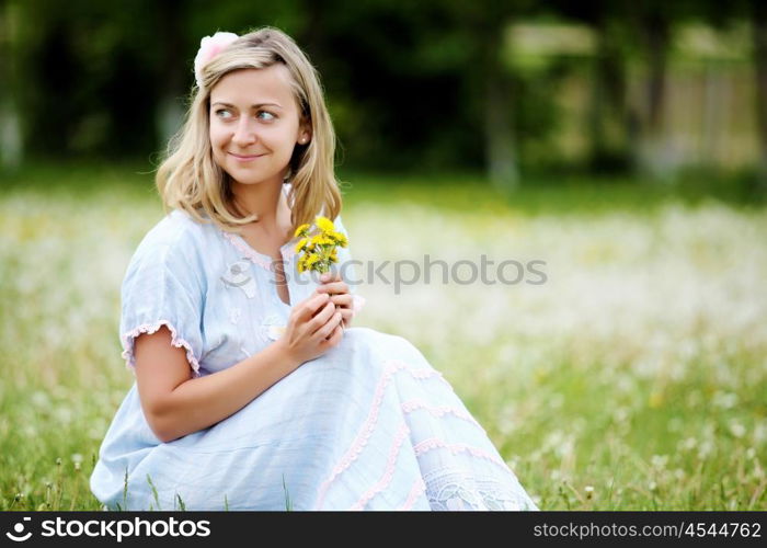 Young blond woman in blue dress in the park