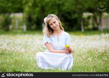 Young blond woman in blue dress in the park